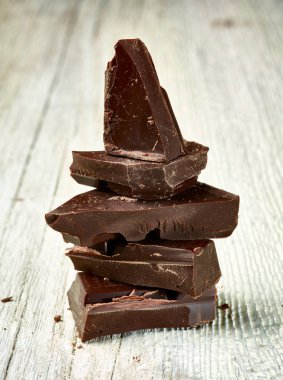 Tahta arka planda çikolata parçalarını kapat