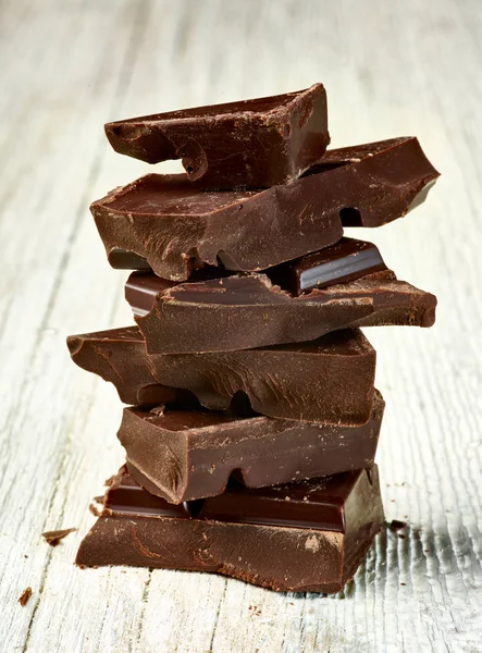 Tahta arka planda çikolata parçalarını kapat