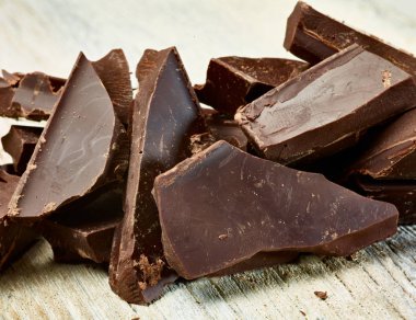 Tahta arka planda çikolata parçalarını kapat