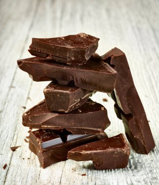 Tahta arka planda çikolata parçalarını kapat