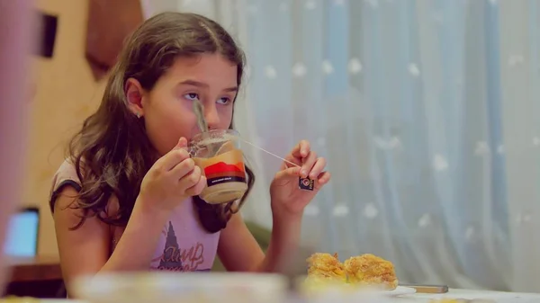 teen girl drinking the tea and eating cake, indoor lifestyle watching tv television at breakfast dinner