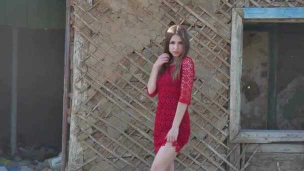 Krásná dívka v červených šatech. Sexy dívka v šatech stojí vedle starého domu ve stylu ruiny