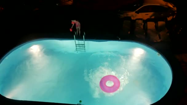 Rapaz e rapariga tomam banho na piscina à noite. Crianças divertimento nadar na água — Vídeo de Stock