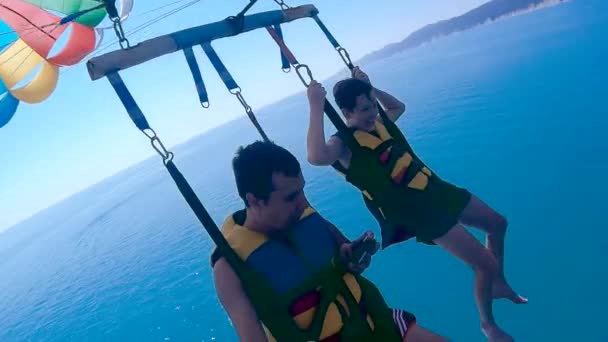 Paragliding a parasailing životní styl. muž a chlapec jsou létání na padáku oceánu nad mořem. Extrémní sport first-person pohled — Stock video