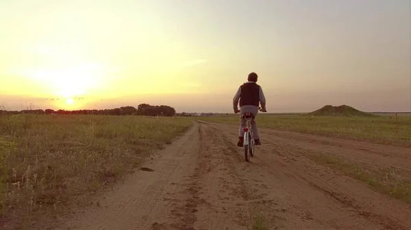 Boy teenager riding a bicycle. Boy teenager riding a bicycle goes to nature along the path steadicam shot video motion