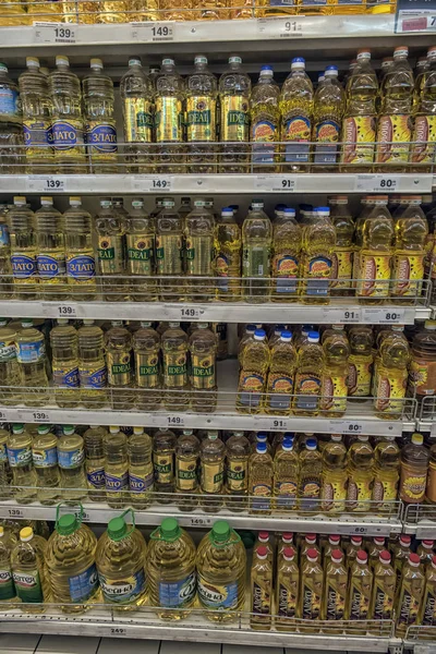 Uma série de garrafas de óleo de girassol, azeite e outros tipos. Estantes horizontais. Interior de uma loja de supermercados . — Fotografia de Stock