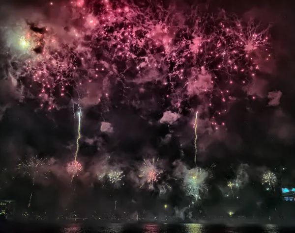 Abstract, blurry, bokeh-style colorful photo of fireworks above the river in New Year — Stock Photo, Image