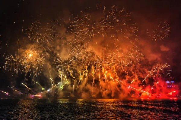 Abstract, blurry, bokeh-style colorful photo of fireworks above the river in New Year — Stock Photo, Image