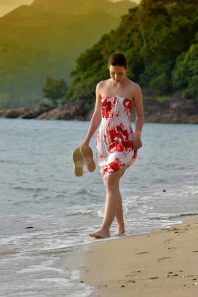 少女は 彼女の手で靴とビーチを歩いています — ストック写真