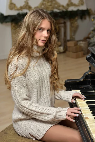Дівчина-підліток у в'язаному светрі на піаніно — стокове фото
