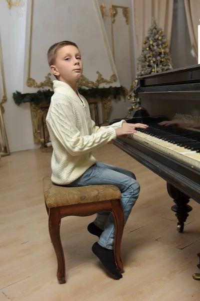 Junge im weißen Strickpullover am Klavier — Stockfoto