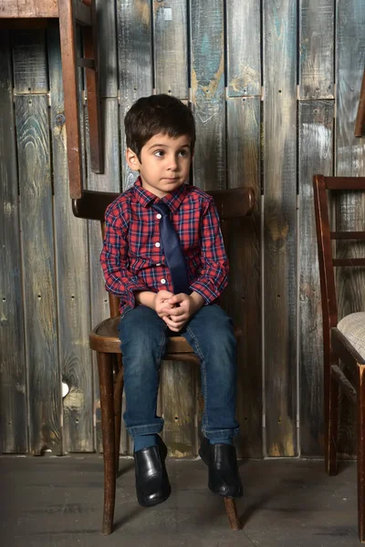 椅子に座っている格子縞のシャツで悲しい少年 — ストック写真