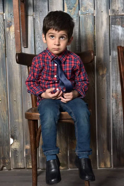 Smutný kluk v kostkované košili sezení — Stock fotografie