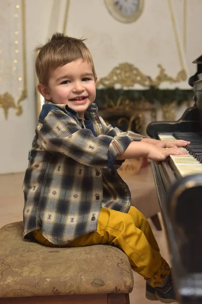 Χαριτωμένο Μικρό Αγόρι Κάθεται Στην Καρέκλα Και Παίζει Στο Πιάνο — Φωτογραφία Αρχείου