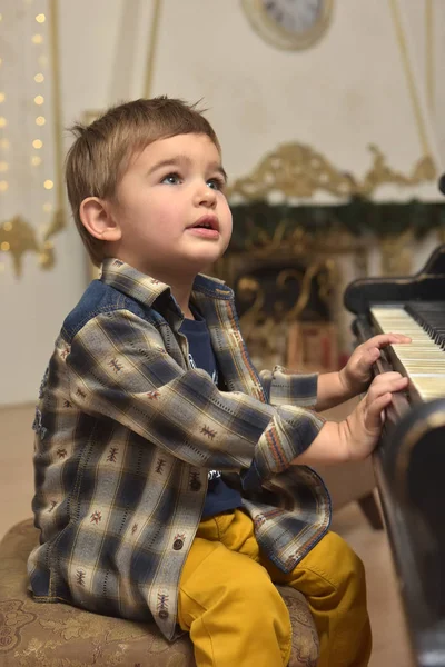 Bambino, seduto sulla sedia e che suona il pianoforte — Foto Stock