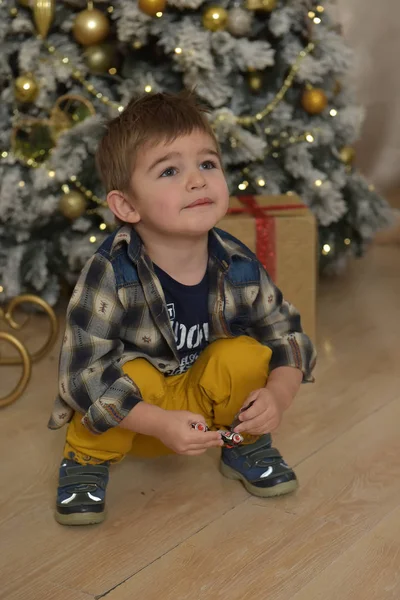 クリスマスツリーの近くで遊んだシャツを着た小さなブルネットの男の子 — ストック写真