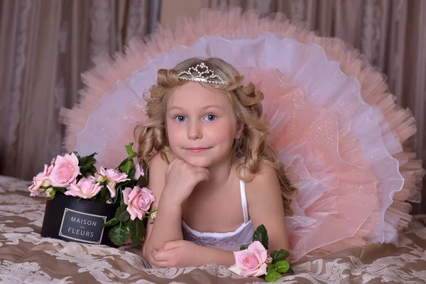 Chica en blanco con vestido rosa y en una diadema en un sofá — Foto de Stock