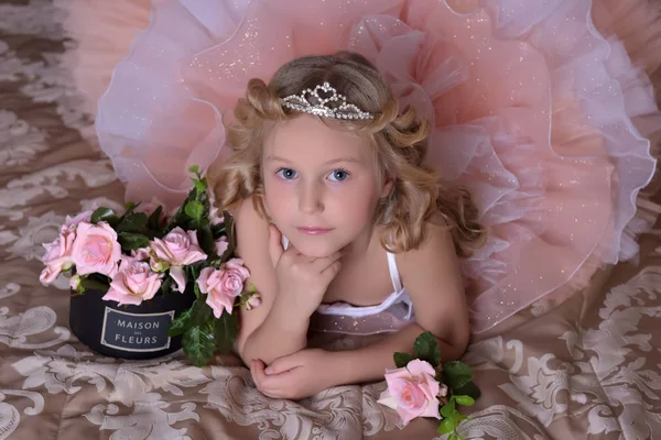 Menina em branco com vestido rosa e em um diadema em um sofá — Fotografia de Stock