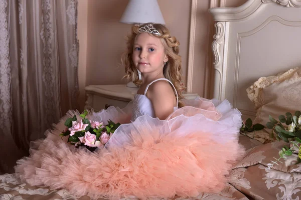 Ragazza in bianco con abito rosa e in un diadema su un divano — Foto Stock