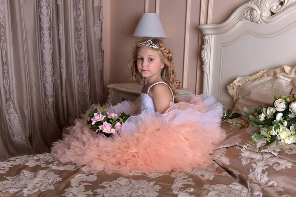 穿白色衣服的女孩穿着粉红色的连衣裙, 穿着沙发上的王冠。 — 图库照片