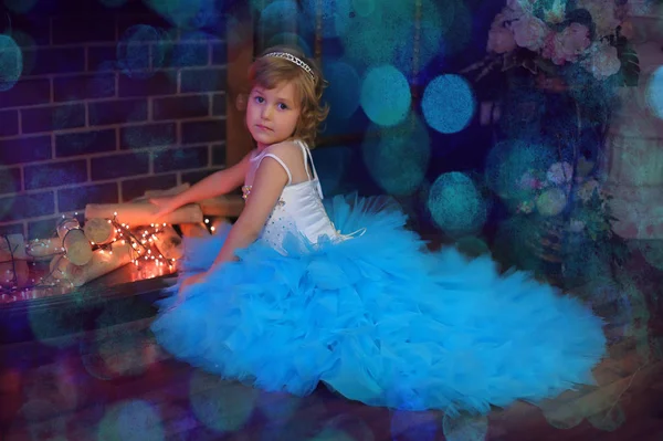 圣诞节时 一个穿着蓝色衣服的女孩在一个发光的壁炉旁 — 图库照片
