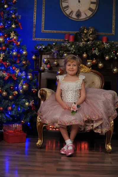 Fille en blanc avec robe rose assis dans la chaise près de Noël tr — Photo