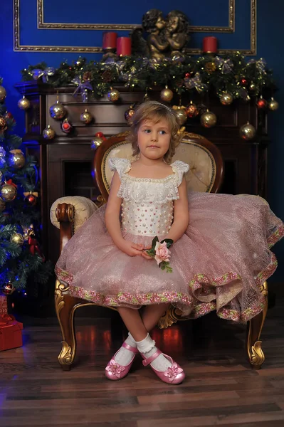 Κορίτσι σε λευκό με ροζ φόρεμα να κάθεται στην πολυθρόνα κοντά Χριστούγεννα tr — Φωτογραφία Αρχείου