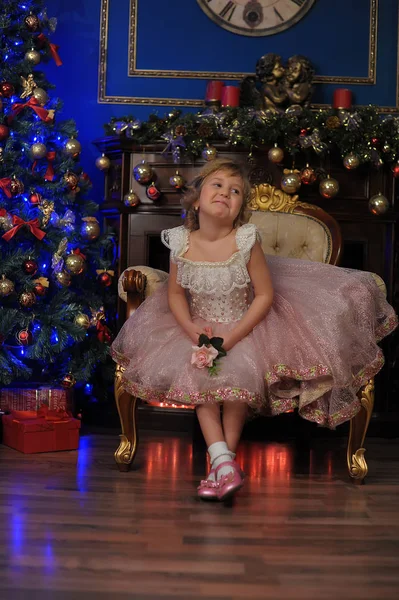 Dívka v bílém s růžové šaty sedí v křesle u vánoční tr — Stock fotografie