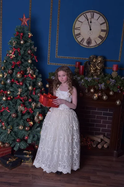 Flicka i en smart vit klänning på en julgran — Stockfoto