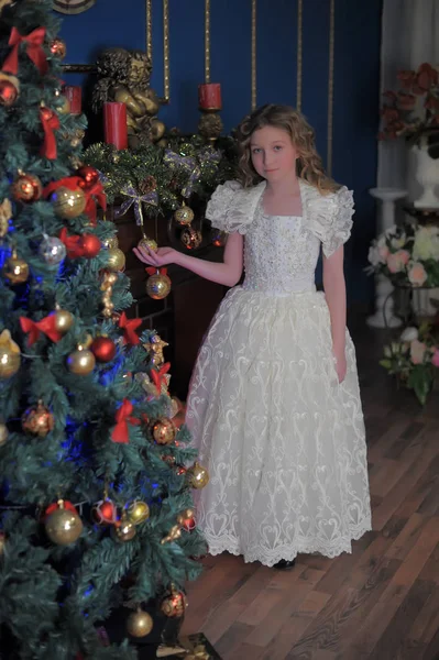 Menina em um vestido branco inteligente em uma árvore de Natal — Fotografia de Stock