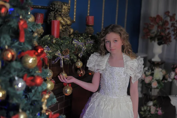 Meisje in een slimme witte jurk op een kerstboom — Stockfoto