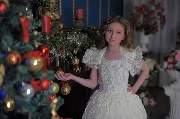 Menina em um vestido branco inteligente em uma árvore de Natal — Fotografia de Stock