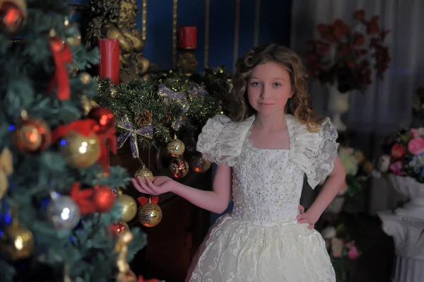Meisje in een slimme witte jurk op een kerstboom — Stockfoto