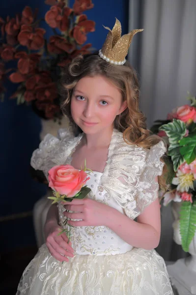 Princezna v bílých šatech s korunou na hlavě a květiny — Stock fotografie
