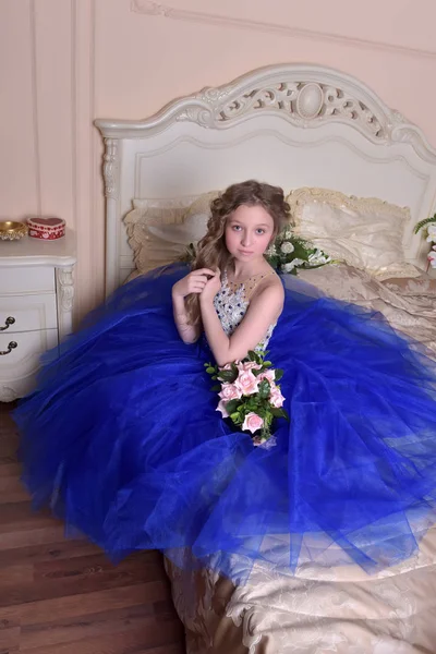 Junge Prinzessin in einem blauen Kleid sitzt mit einem Strauß von ros — Stockfoto