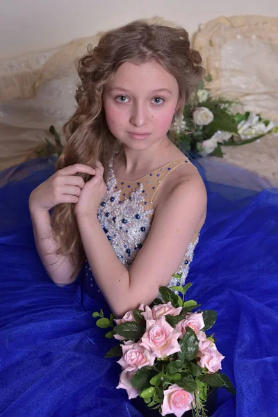 Unga prinsessan i en blå klänning sitter med en bukett av ros — Stockfoto
