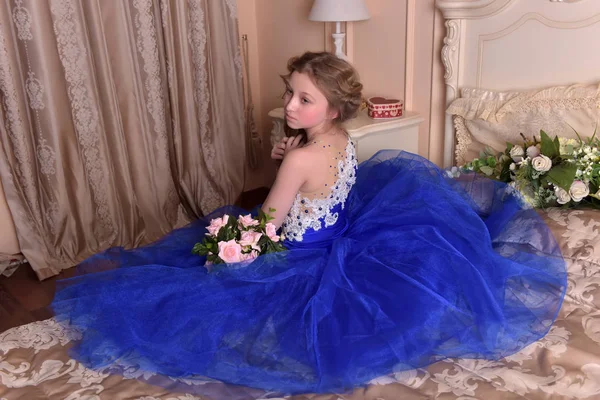 Młoda księżniczka w niebieskiej sukience siedzi z bukietem ros — Zdjęcie stockowe