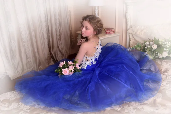 Egy kék ruhás ifjú hercegnő ül egy-egy csokor ros — Stock Fotó