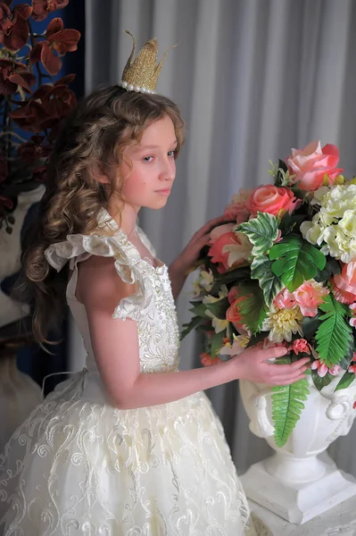 Prinsessan i en vit klänning med en krona på hennes huvud och blommor — Stockfoto