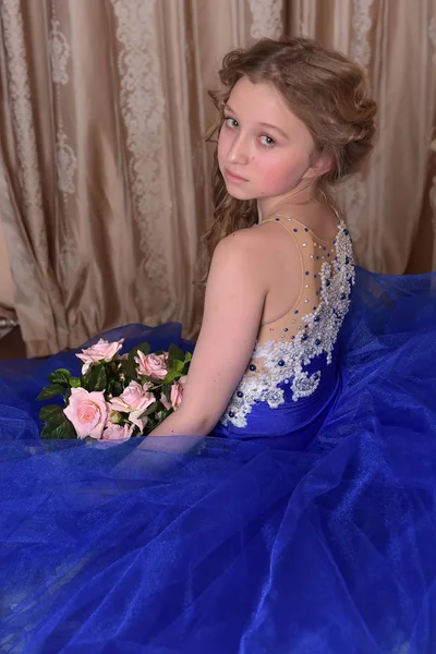 穿着蓝色连衣裙的年轻公主坐着一束 ros — 图库照片
