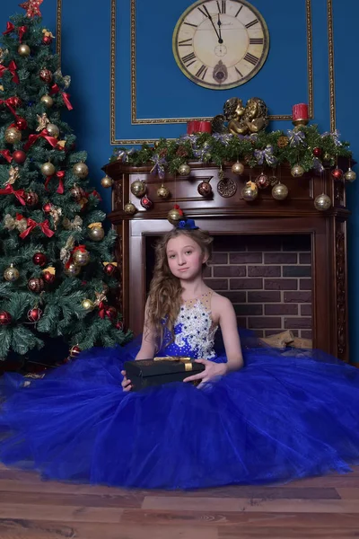 Девушка в синем платье сидит у камина на Рождество — стоковое фото