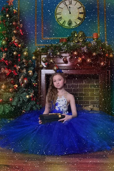 Fille en robe bleue se trouve près de la cheminée au moment de Noël — Photo