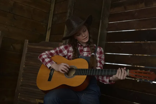 A girl in a cowboy hat and plaid shirt — Stock Photo, Image