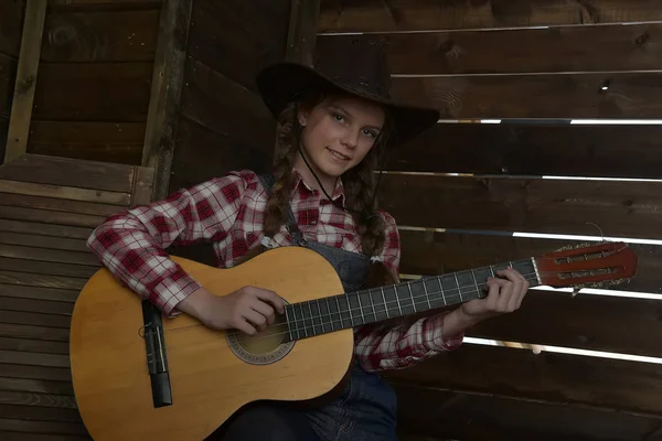 A girl in a cowboy hat and plaid shirt — Stock Photo, Image