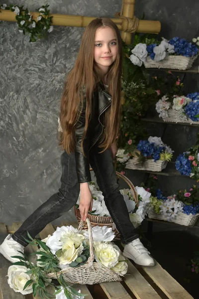 Jong meisje in een zwarte leren jas met bloemen — Stockfoto
