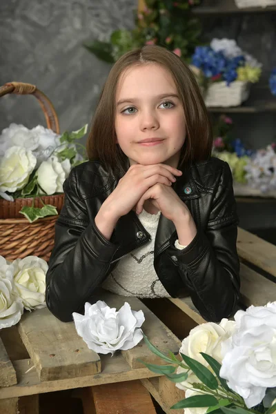 Jeune fille dans une veste en cuir noir avec des fleurs — Photo