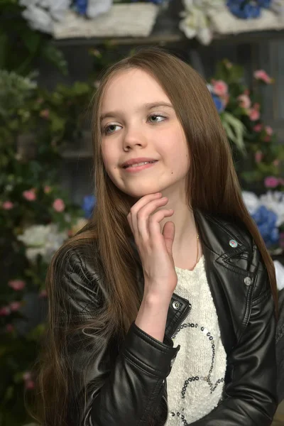 Jeune fille dans une veste en cuir noir avec des fleurs — Photo