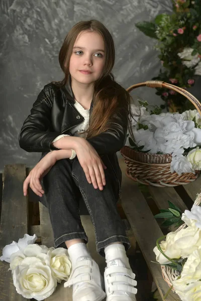 Jeune fille dans une veste en cuir noir avec des fleurs — Photo