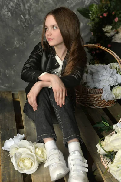 Молода дівчина в чорній шкіряній куртці з квітами — стокове фото