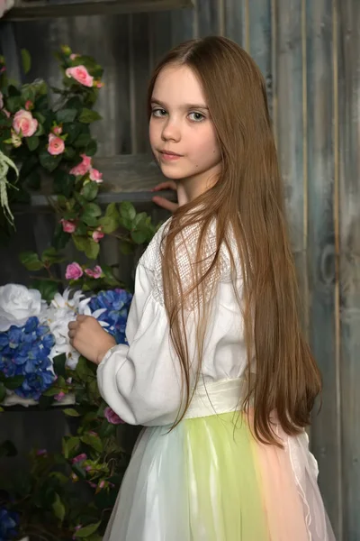 Joven morena de pelo rubio en blusa blanca junto a las flores —  Fotos de Stock